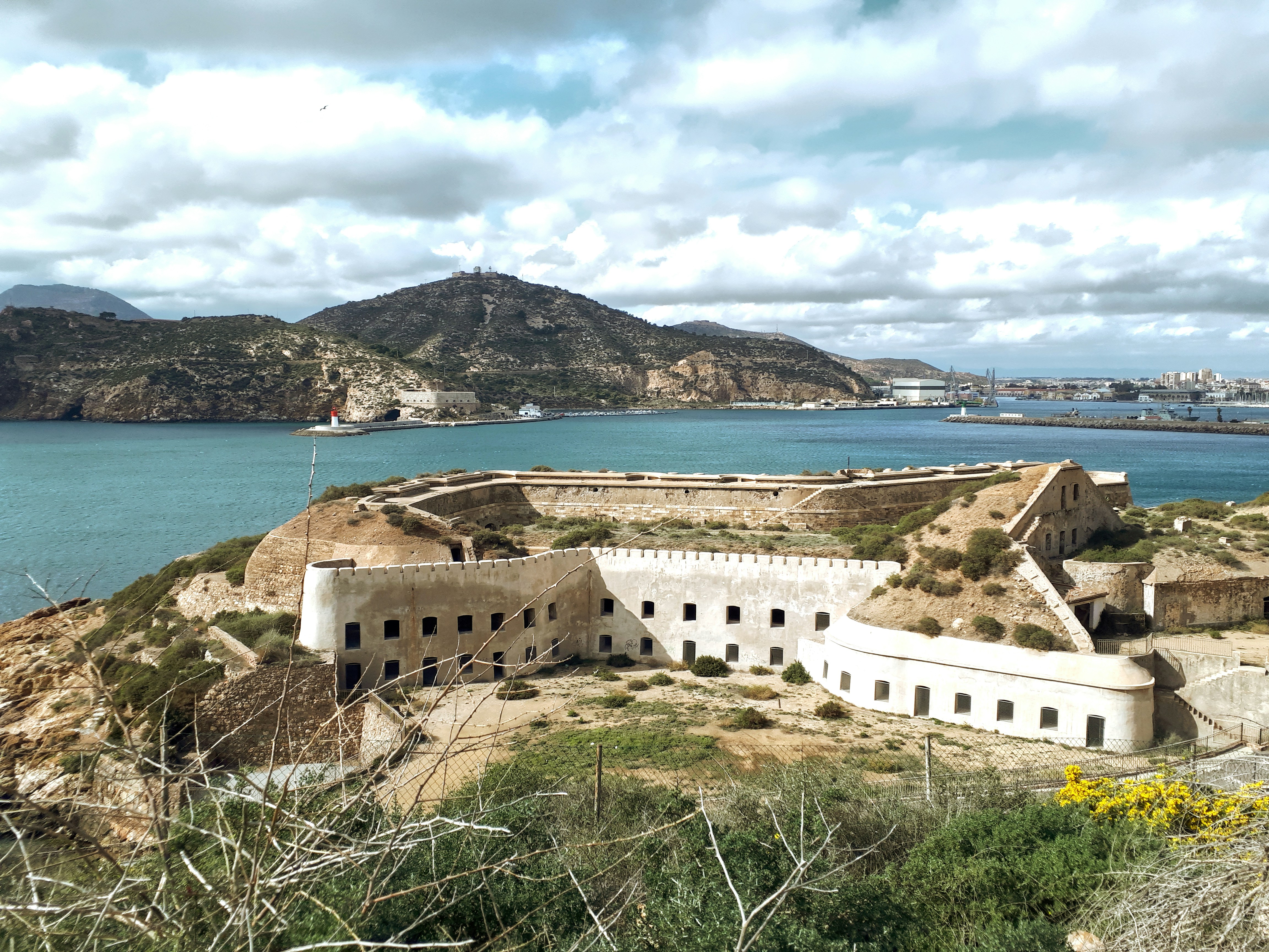 Historic fortifications above Cartagena harbour, with the Mediterranean coast and city in the distance.